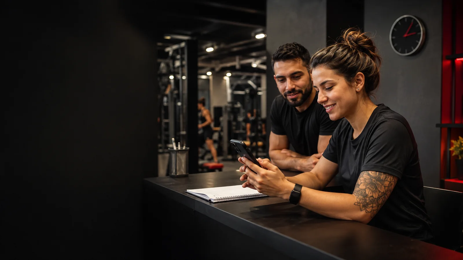 Equipe de academia conferindo uma conversa no celular para dar continuidade ao atendimento.